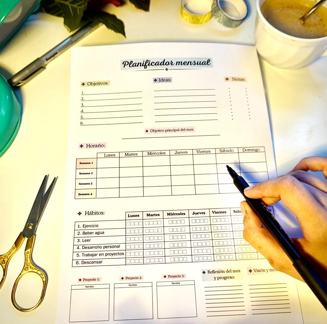 Mano escribiendo sobre el planificador mensual imprimible
