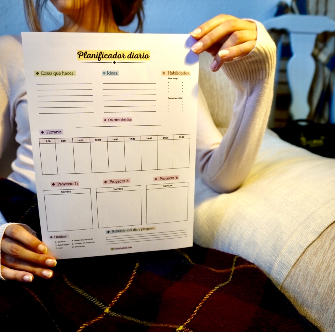 Mujer joven sostiene el planificador diario de Triunfonline con fondo neutro, mostrando su diseño elegante y minimalista